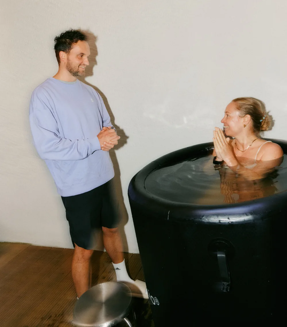 A coach at the ice bath, a participant sitting in the water