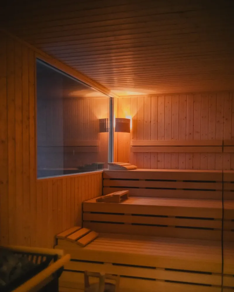 Die Sauna mit gestuften Bänken, warmem Licht und dem Aufgusskübel