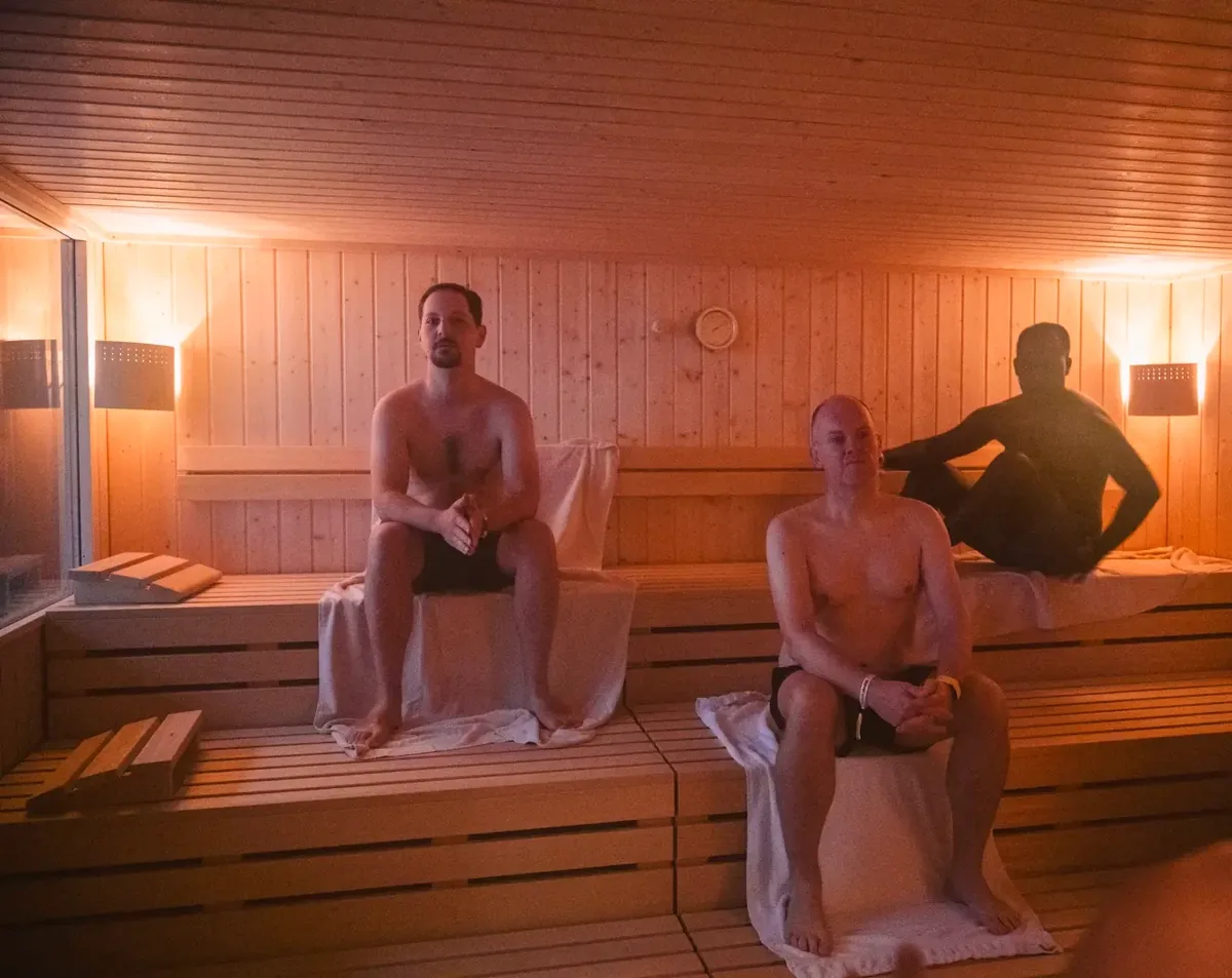 Drei Personen auf den Baenken der finnischen Sauna